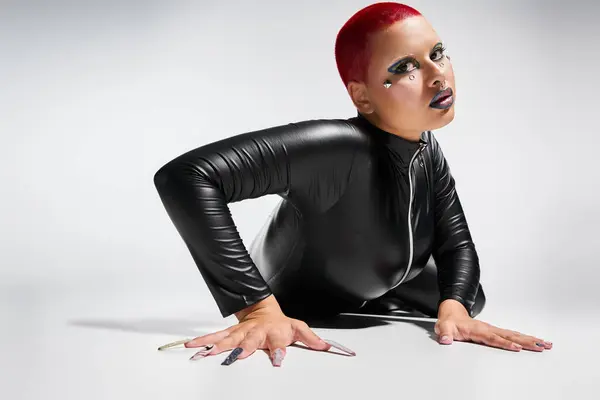 A bold individual with short pink hair showcases unique style while striking an expressive pose indoors. — Stock Photo