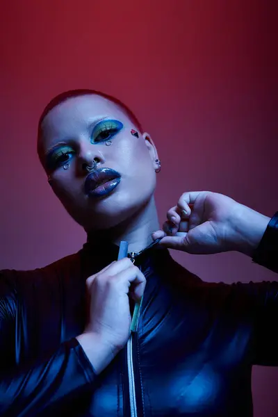 Una joven mujer muestra su aspecto llamativo con maquillaje colorido y accesorios vívidos en un estudio. - foto de stock