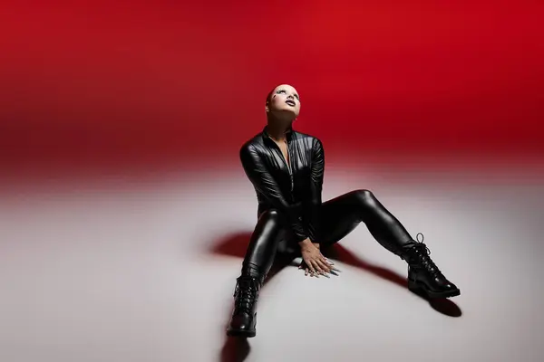 In a striking studio, a young woman flaunts her pink hair and edgy outfit while striking a powerful pose. — Stock Photo