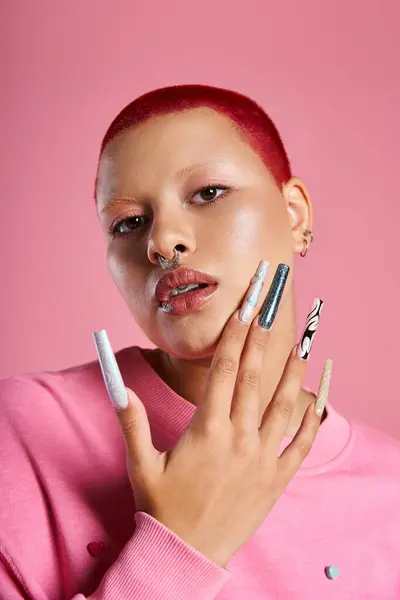 A confident young woman with striking pink hair and distinct nails expresses her unique style in a studio. — Stock Photo