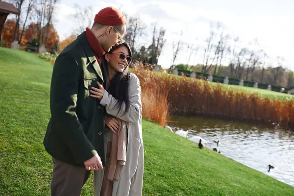 A couple enjoys a loving embrace, dressed warmly as autumn leaves fall around them. — Stock Photo