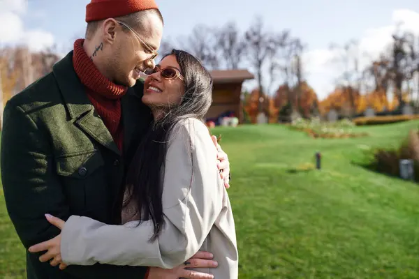 Wrapped in cozy autumn attire, a couple shares a tender moment amidst colorful fall foliage. — Stock Photo