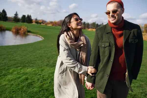 Amidst beautiful fall foliage, the couple shares laughter and affection while walking hand in hand. — Stock Photo