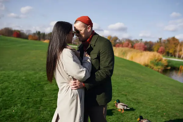 A couple shares a warm moment surrounded by beautiful autumn foliage and gentle lake breezes. — Stock Photo