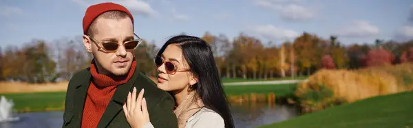 Under the warm autumn sun, a couple shares a loving moment near a tranquil lake. — Stock Photo