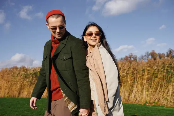 Enveloppé dans des vêtements chauds, un couple partage un moment joyeux tout en marchant à travers le feuillage d'automne. — Photo de stock