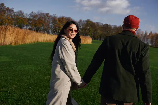 A couple walks hand in hand in a serene autumn landscape, wrapped in warm attire and smiles. — Stock Photo