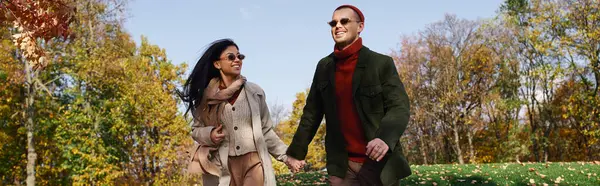 A loving couple walks hand in hand through vibrant autumn trees, enjoying each others company. — Foto stock