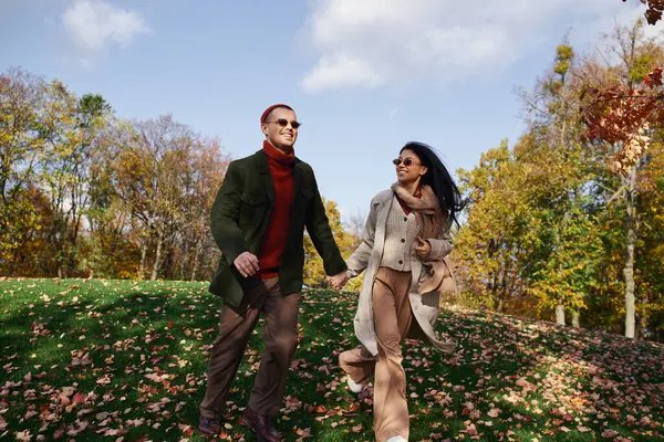 Two loving individuals enjoy a walk amidst falling leaves, clad in cozy autumn attire. — Stock Photo