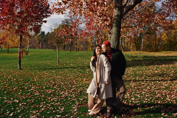 A couple enjoys an affectionate moment outdoors, surrounded by colorful autumn leaves. — Stock Photo