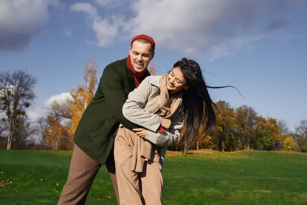 A couple shares a loving moment dressed in cozy autumn outfits, surrounded by vibrant fall foliage. — Stock Photo