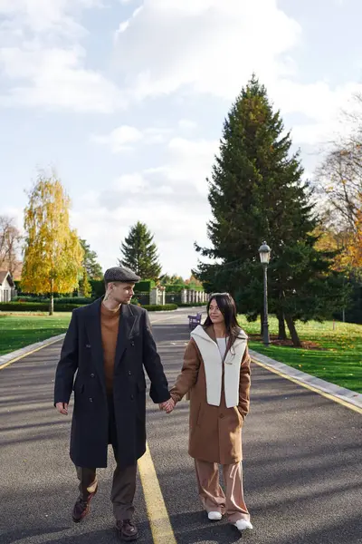 Two affectionate individuals walk together, wrapped in cozy attire, surrounded by autumn hues. — Foto stock