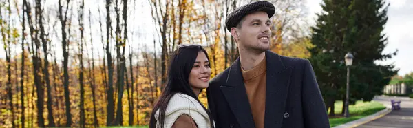 A cozy couple strolls through a sunlit park, surrounded by colorful autumn leaves. — Stock Photo