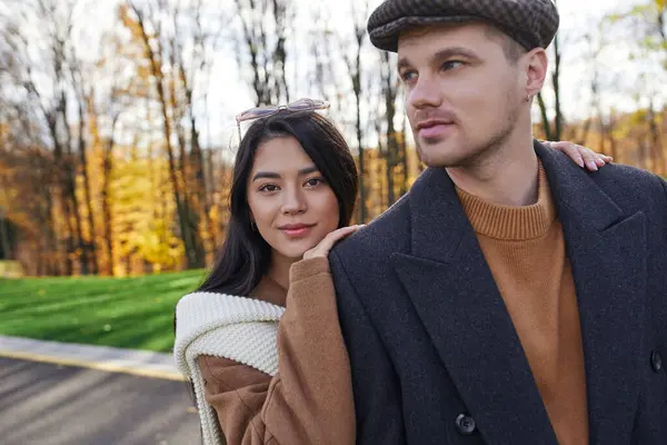 A couple enjoys a beautiful autumn day, wrapped in cozy attire amidst colorful foliage. — Stock Photo
