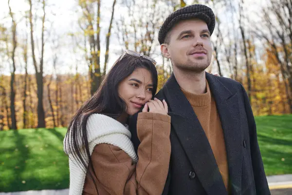 A couple sharing a tender moment amidst vibrant autumn foliage, showcasing their affection. — Stock Photo