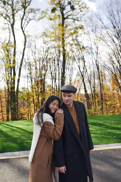 In a beautiful autumn setting, a couple enjoys an intimate moment, wrapped in cozy outfits. — Stock Photo
