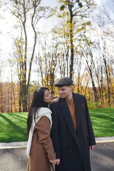 A couple enjoys a tender moment outdoors, dressed warmly amidst the vibrant autumn colors. — Stock Photo