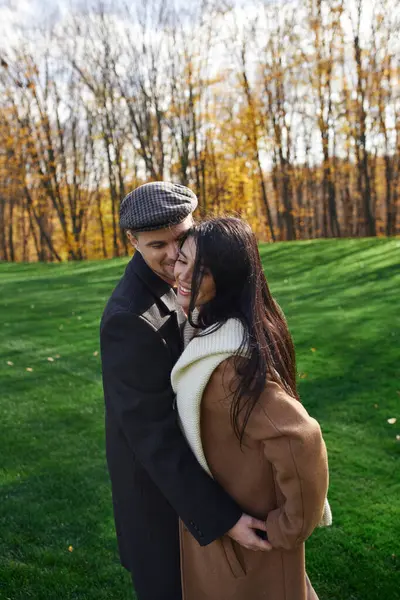 A couple shares a joyful embrace, dressed warmly for a beautiful autumn day. — Stock Photo