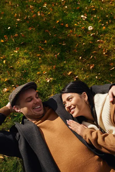 A couple relaxes together on a grassy patch, enjoying each others warmth amidst autumns beauty. — Stock Photo