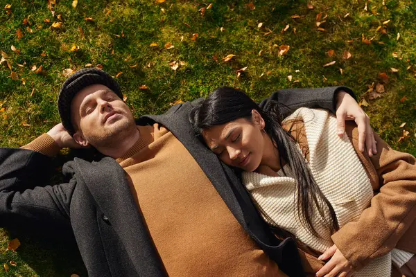 A loving couple relaxes under the autumn sun, surrounded by vibrant leaves and nature. — Stock Photo