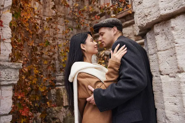 A couple enjoys a tender moment in warm autumn clothing amidst colorful fall foliage. — Stock Photo