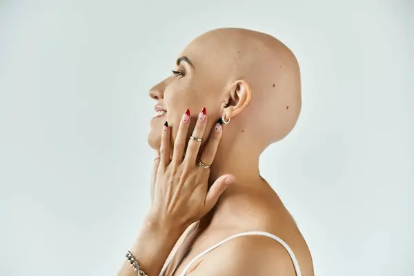 A young bald woman embraces her beauty with a serene smile and graceful touch. — Stock Photo