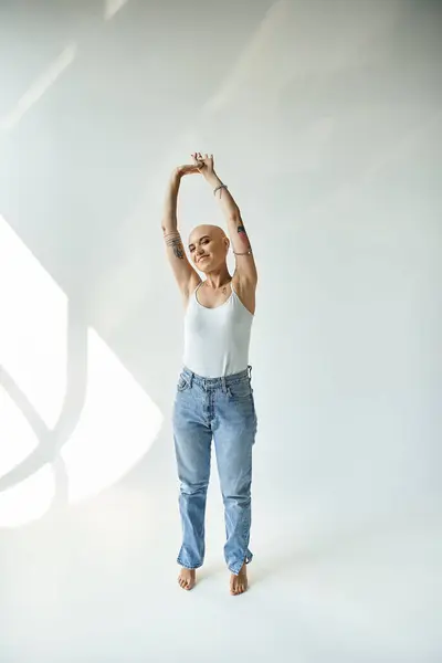 A bald woman with alopecia stretches elegantly, highlighting her confidence and beauty. — Stock Photo