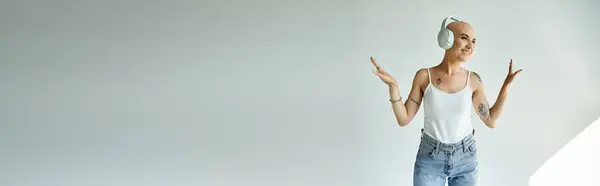 A young woman with alopecia radiates happiness as she enjoys her music in a minimalist space. — Stock Photo
