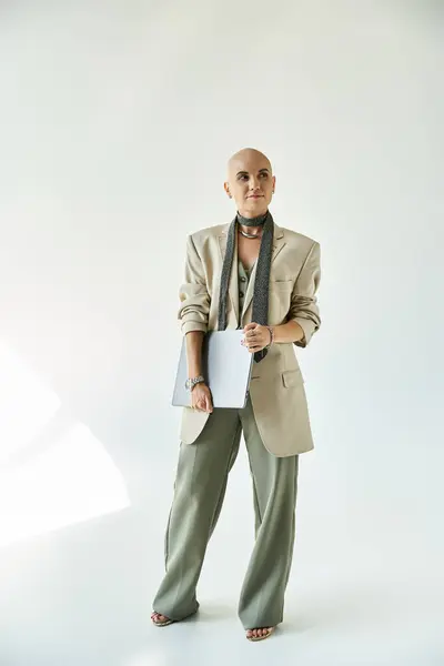 A young bald woman exudes confidence in a chic outfit, standing against a minimalistic backdrop. — Stock Photo