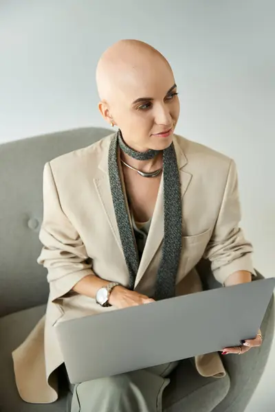 A confident young bald woman works on her laptop, showcasing her unique style and resilience. — Stock Photo