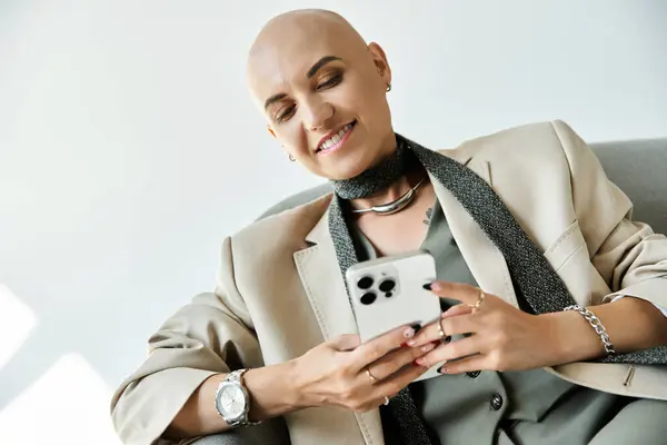 A confident young woman with a bald head enjoys browsing her smartphone, radiating positivity. — Stock Photo