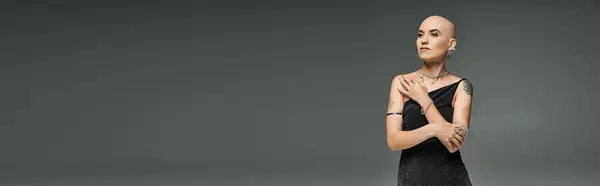 A confident young woman embraces her baldness while showcasing her unique beauty in a black dress. — Stock Photo