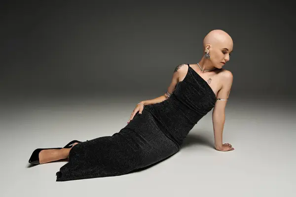 A young bald woman showcases her beauty while elegantly posed in a striking black gown. — Stock Photo