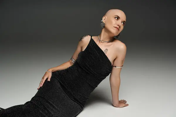 A young bald woman with alopecia poses elegantly in a sleek black gown, exuding confidence. — Stock Photo