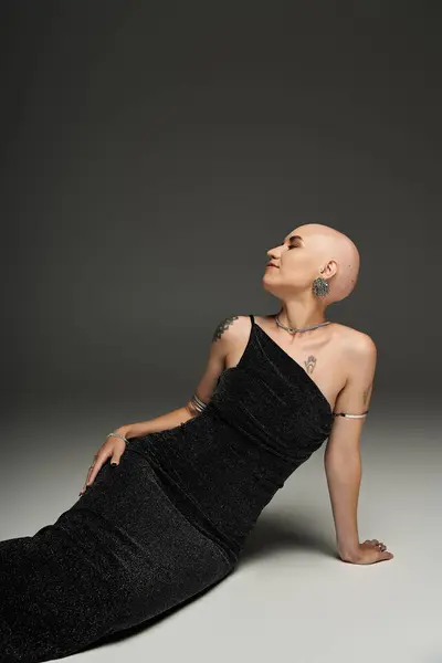 A young bald woman with alopecia elegantly poses in a stylish black gown, radiating confidence. — Stock Photo