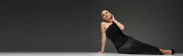Una joven calva posa graciosamente en un elegante vestido negro, irradiando fuerza y elegancia. - foto de stock