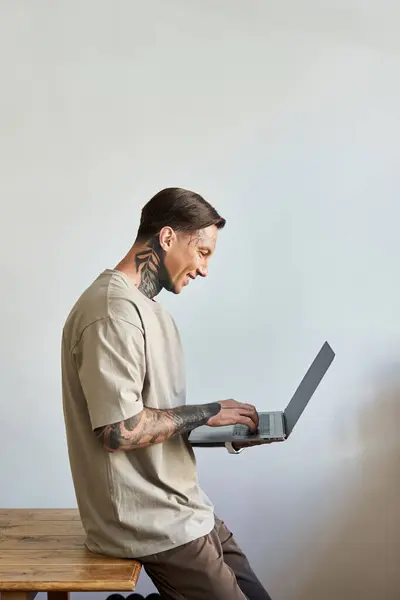 The young man, with unique tattoos, is absorbed in work, radiating joy and creativity at home. — Stock Photo
