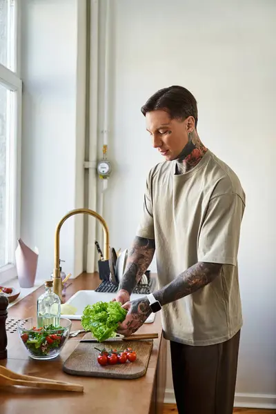 In a bright kitchen, a young man skillfully chops lettuce, embracing healthy cooking. — Stock Photo