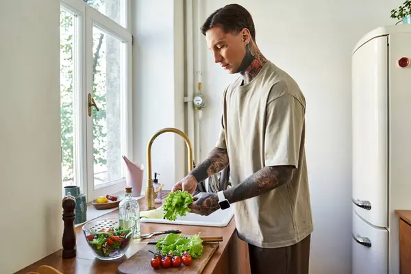 A handsome young man skillfully chops vegetables in his cozy kitchen, embracing healthy living. — Stock Photo