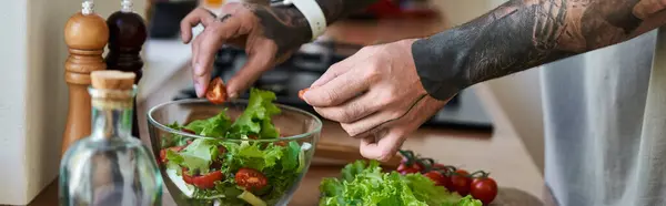 A young, handsome man skillfully mixes fresh vegetables in a bowl while cooking at home. — Stock Photo