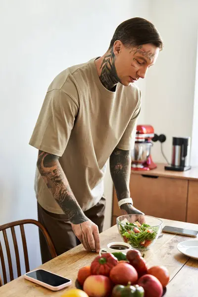 A handsome young man focuses on creating a colorful salad in his inviting kitchen space. — Stock Photo