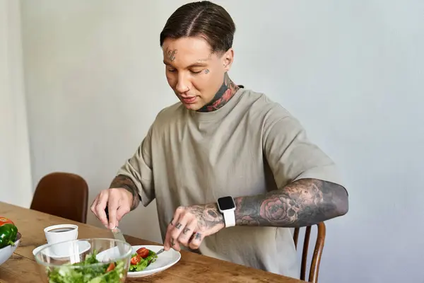 A stylish young man sits at a wooden table, savoring a nutritious meal with concentration. — Stock Photo