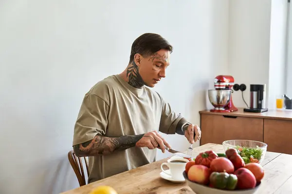 In a cozy kitchen, a young man savors a wholesome meal while preparing fresh ingredients. — Stock Photo