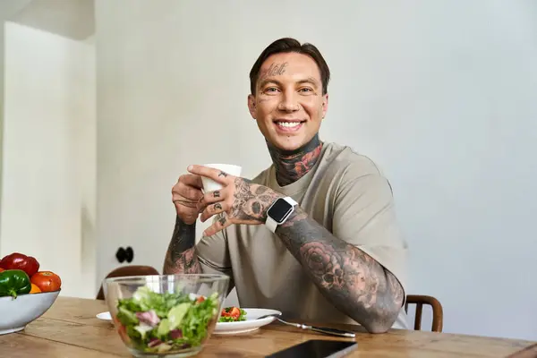 A captivating young man sits at a wooden table, savoring a meal with a warm smile. — Stock Photo