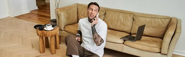 The young man sits comfortably on the couch, talking on the phone and enjoying a peaceful moment. — Stock Photo