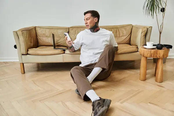 Un jeune homme se prélasse à la maison, faisant défiler son téléphone tout en profitant d'un moment paisible. — Photo de stock