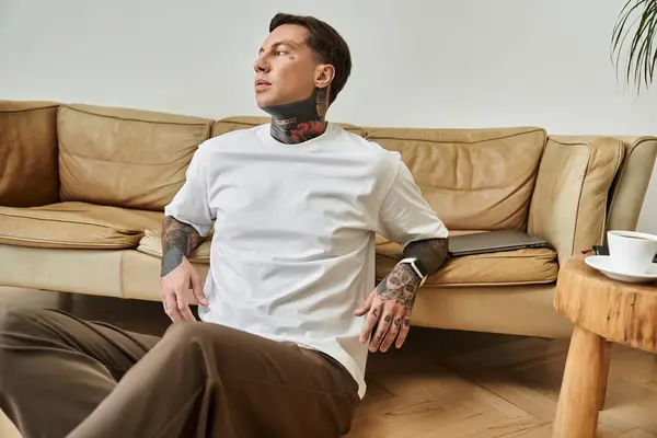 The handsome man relaxes indoors, showing off his tattoos in a peaceful moment. — Stock Photo
