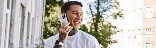 A handsome young man shares a joyful moment during a phone call at his bright home. — Stock Photo