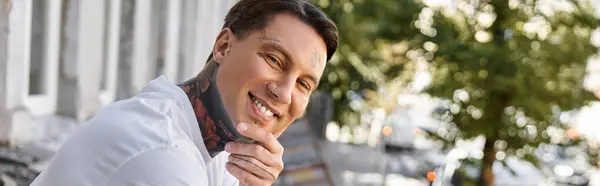 In a cozy home setting, a young man smiles joyfully while resting during daylight hours. — Stock Photo