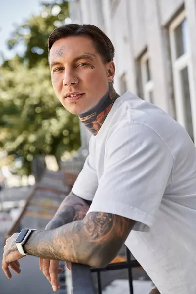 A handsome young man leans casually against the railing at home, exuding confidence and style. — Stock Photo